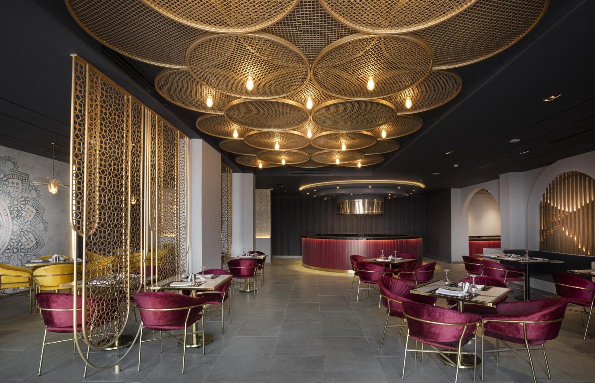 V Hotel Sharm El Shiekh Esterno foto The image shows a stylish and modern restaurant interior. The ceiling features a unique design with large, circular patterns that are illuminated by warm lighting. The walls are adorned with a sophisticated, dark color scheme complemented by elegant 